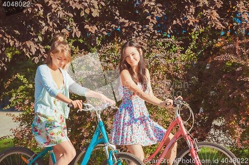 Image of The two young girls with bicycles in park