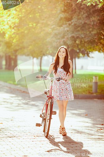 Image of The young girl with bicycle in park