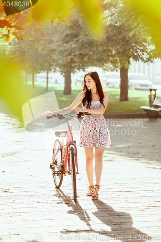 Image of The young girl with bicycle in park