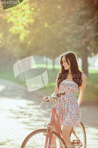 Image of The young girl with bicycle in park