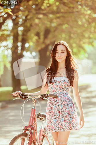 Image of The young girl with bicycle in park
