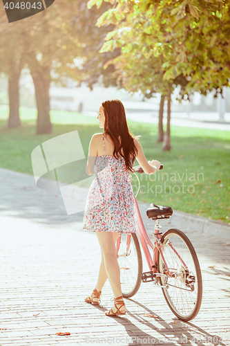 Image of The young girl with bicycle in park