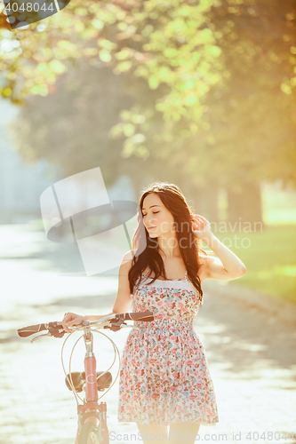 Image of The young girl with bicycle in park