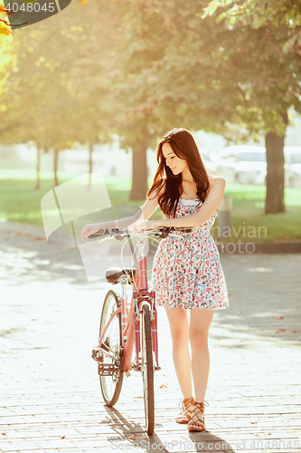 Image of The young girl with bicycle in park