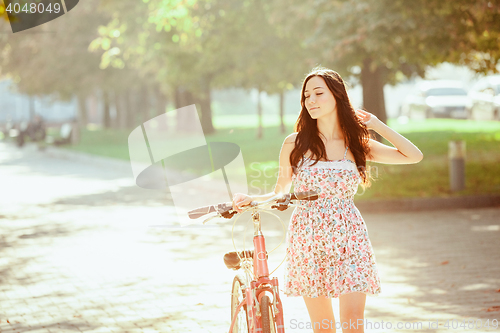 Image of The young girl with bicycle in park
