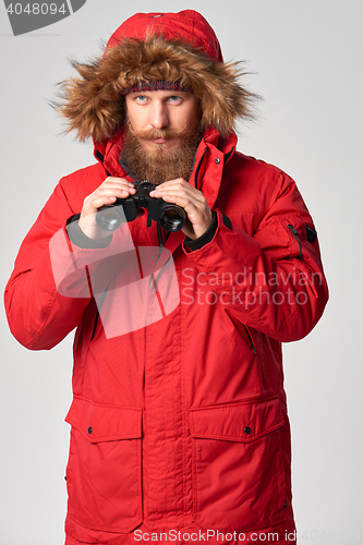 Image of Man wearing red winter jacket with binoculars