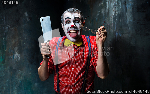 Image of The scary clown holding a knife on dack. Halloween concept