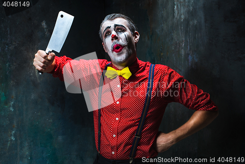 Image of The scary clown holding a knife on dack. Halloween concept