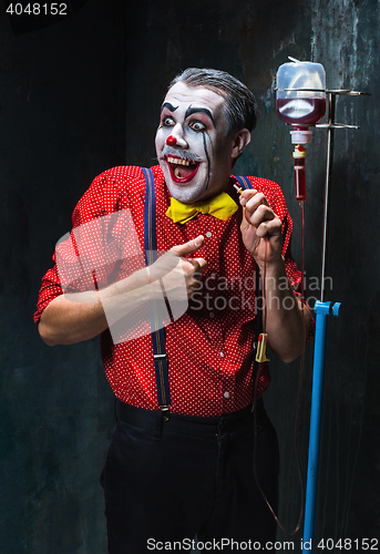 Image of The scary clown and drip with blood on dack background. Halloween concept