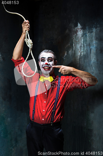 Image of The scary clown and rope for hanging on dack background. Halloween concept