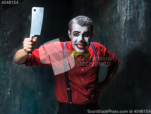 Image of The scary clown holding a knife on dack. Halloween concept