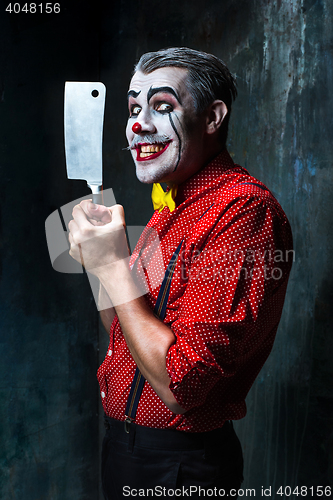 Image of The scary clown holding a knife on dack. Halloween concept