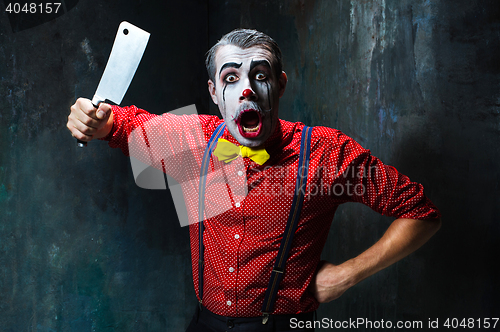 Image of The scary clown holding a knife on dack. Halloween concept