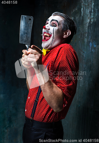 Image of The scary clown holding a knife on dack. Halloween concept