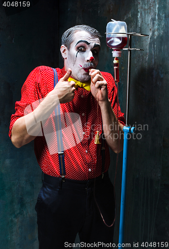 Image of The scary clown and drip with blood on dack background. Halloween concept