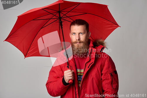 Image of Man in red winter jacket standing with umbrella