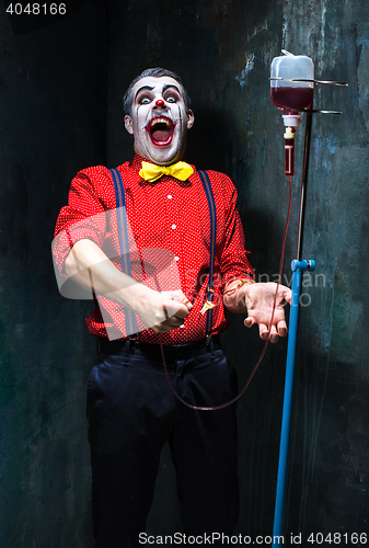 Image of The scary clown and drip with blood on dack background. Halloween concept