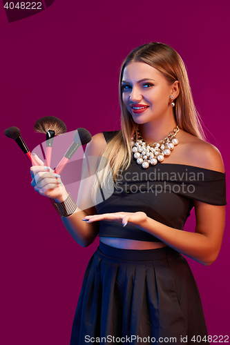 Image of Woman makeup artist standing with brushes