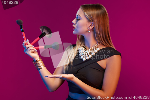 Image of Woman makeup artist standing with brushes