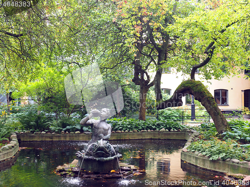 Image of park with pond and statue fountain off shopping street Drottning