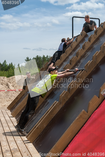 Image of Athlete gets on inclined wall by means of bar