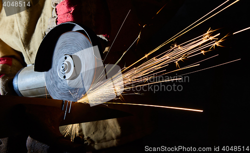 Image of Worker cutting metal with grinder. Sparks while grinding iron