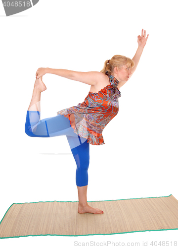 Image of Yoga trainer standing on one leg .