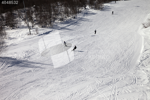 Image of Skiers and snowboarders on ski slope at sun winter day