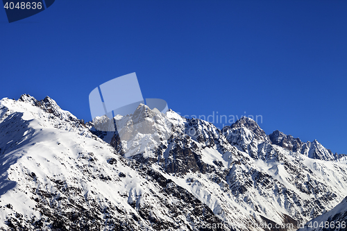 Image of Snowy rocks and blue clear sky at cold sun day