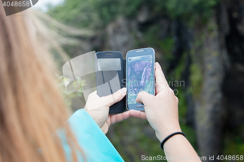 Image of Woman photographing a waterfall with a mobile phone