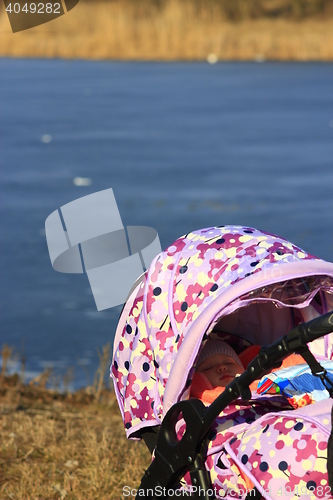 Image of little baby sleeps in perambulator near the river