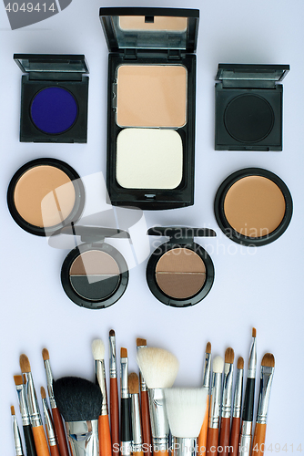 Image of makeup brush and cosmetics, on a white background