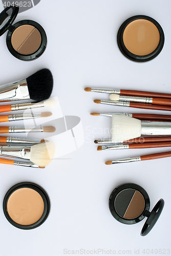 Image of makeup brush and cosmetics, on a white background