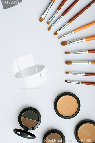 Image of makeup brush and cosmetics, on a white background