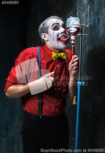 Image of The scary clown and drip with blood on dack background. Halloween concept