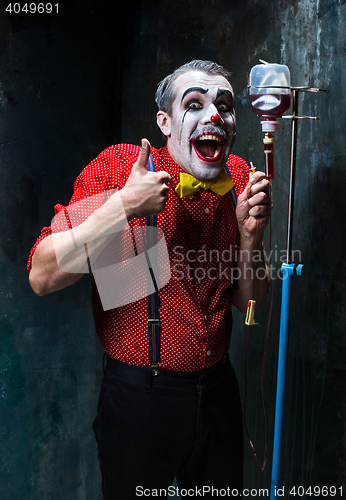 Image of The scary clown and drip with blood on dack background. Halloween concept