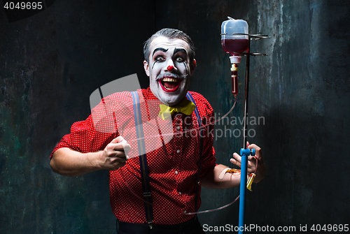 Image of The scary clown and drip with blood on dack background. Halloween concept