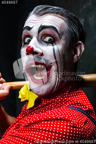 Image of The scary clown and baseball-bat on dack background. Halloween concept