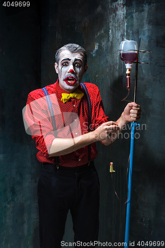 Image of The scary clown and drip with blood on dack background. Halloween concept