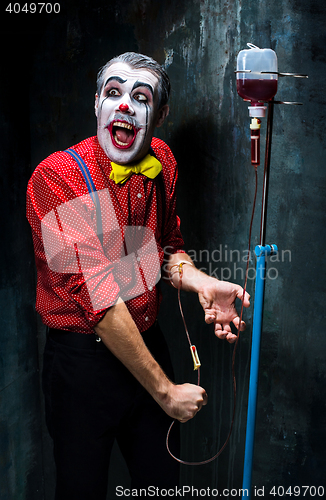 Image of The scary clown and drip with blood on dack background. Halloween concept