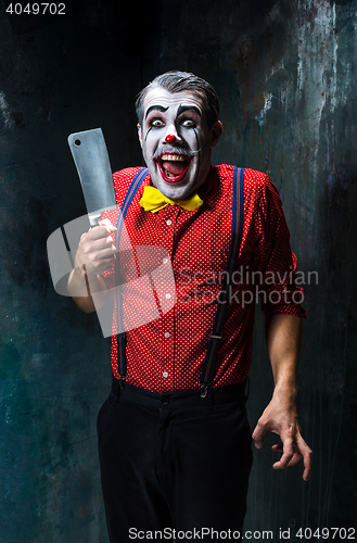 Image of The scary clown holding a knife on dack. Halloween concept