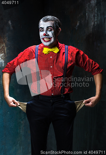 Image of Terrible clown and Halloween theme: Crazy red clown in a shirt with suspenders on a dark background