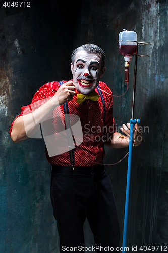 Image of The scary clown and drip with blood on dack background. Halloween concept