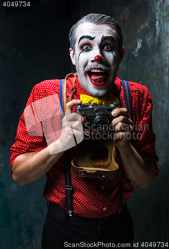 Image of The scary clown and a camera on dack background. Halloween concept