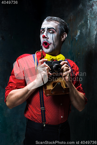 Image of The scary clown and a camera on dack background. Halloween concept