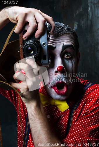 Image of The scary clown and a camera on dack background. Halloween concept