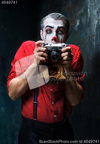 Image of The scary clown and a camera on dack background. Halloween concept