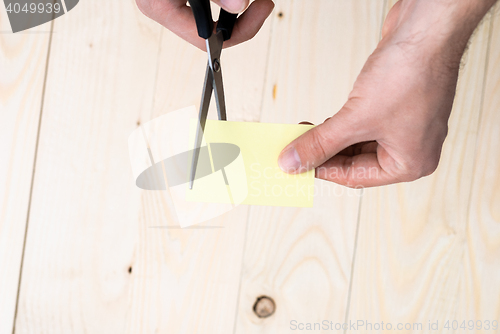 Image of A man is cutting a sheet of yellow paper using metallic scissors