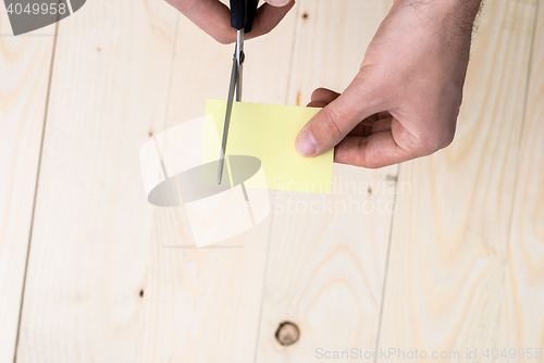 Image of A man is cutting a sheet of yellow paper using metallic scissors