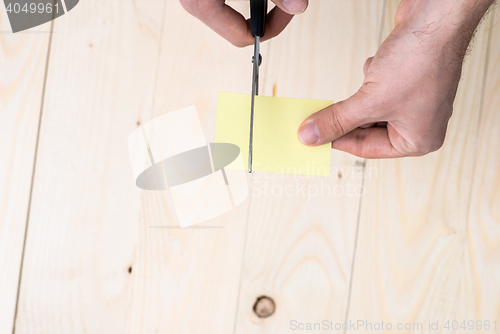 Image of A man is cutting a sheet of yellow paper using metallic scissors